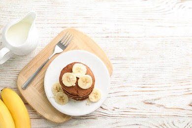 Plate of banana pancakes served on white wooden table, flat lay. Space for text