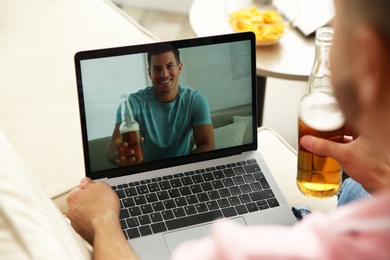 Friends drinking beer while communicating through online video conference at home. Social distancing during coronavirus pandemic
