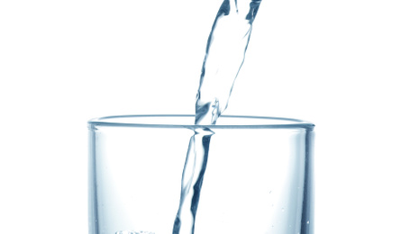 Pouring water into glass on white background, closeup