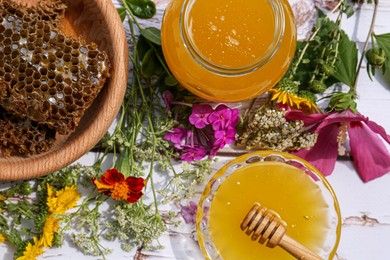 Delicious honey, combs and different flowers on white wooden table, flat lay