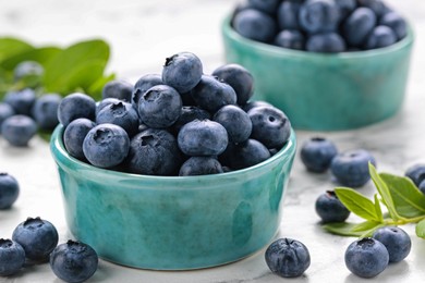 Tasty fresh blueberries on white marble table, closeup