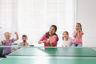 Cute happy children playing ping pong indoors