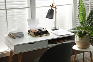 Comfortable writer's workplace with typewriter on desk in front of window