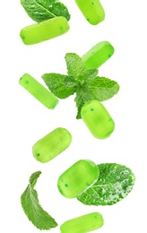 Mint hard candies and green leaves falling on white background 