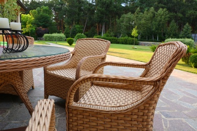 Photo of Rattan armchairs and table at backyard near beautiful garden