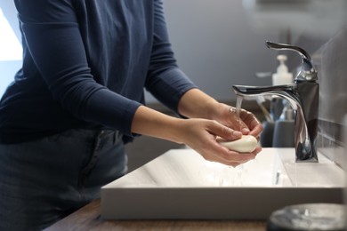 Woman with soap bar washing hands in bathroom, closeup