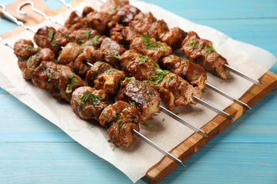 Metal skewers with delicious meat served on light blue wooden table