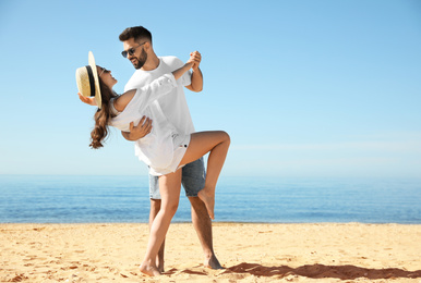 Happy young couple dancing on beach near sea. Honeymoon trip
