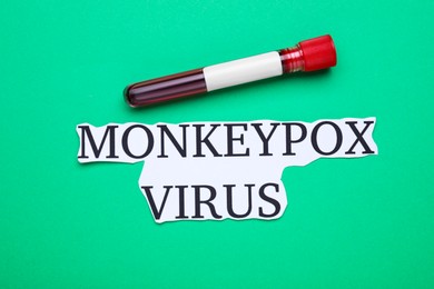 Words Monkeypox Virus and test tube with blood sample on green background, flat lay