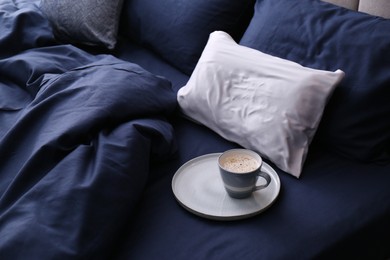 Cup of coffee on bed with stylish silky linens