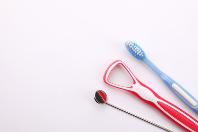 New tongue cleaner, toothbrush and dental mirror on white background, top view