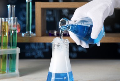 Photo of Scientist working with laboratory glassware indoors, closeup. Chemical reaction