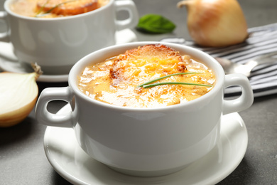 Tasty homemade french onion soup served on grey table, closeup