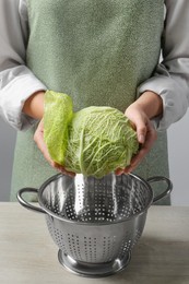 Woman separate leaf from fresh savoy cabbage at wooden table, closeup