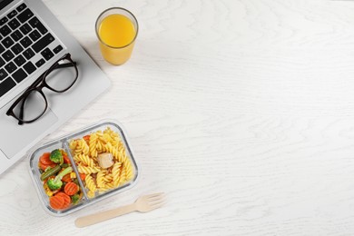 Photo of Container of tasty food, fork, laptop, glass of juice on white wooden table, flat lay with space for text. Business lunch