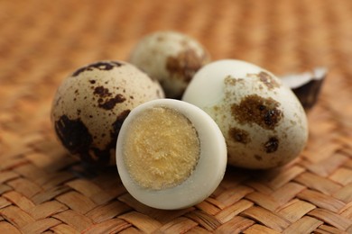 Photo of Unpeeled and peeled hard boiled quail eggs on wicker surface, closeup