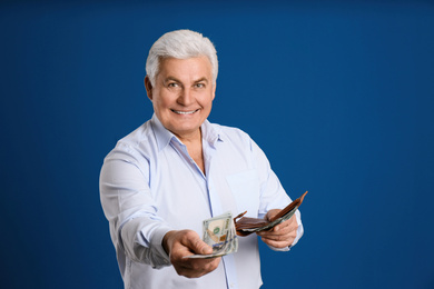 Happy senior man with cash money and wallet on blue background