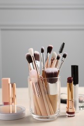 Photo of Set of professional brushes and makeup products on wooden table indoors