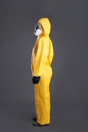 Woman wearing chemical protective suit on grey background. Virus research