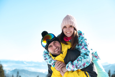 Happy couple spending time on snowy hill in mountains. Winter vacation