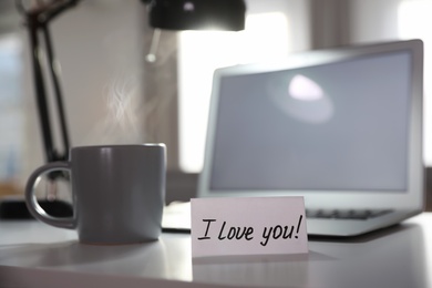 Note with handwritten text I Love You on workplace indoors. Romantic message