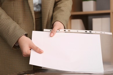 Photo of Businesswoman putting document into punched pocket in office, closeup