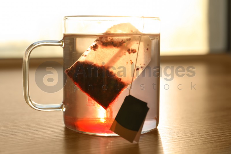 Tea bag in cup of hot water on wooden table, closeup