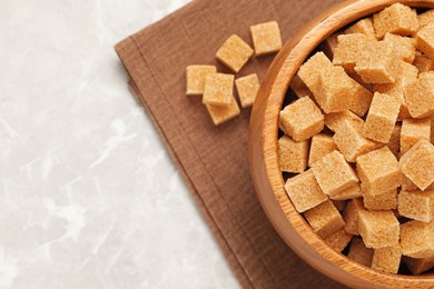 Photo of Brown sugar cubes on light grey marble table, flat lay. Space for text