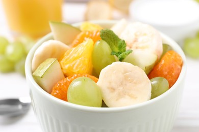 Delicious fresh fruit salad in bowl on table, closeup view