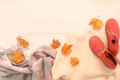 Photo of Flat lay composition with sweater and dry leaves on white wooden background, space for text. Autumn season
