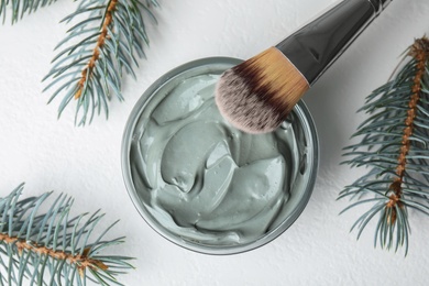 Professional face mask with spruce and brush on white table, flat lay