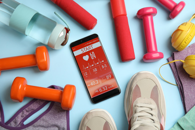 Flat lay composition with fitness equipment and smartphone on light blue background