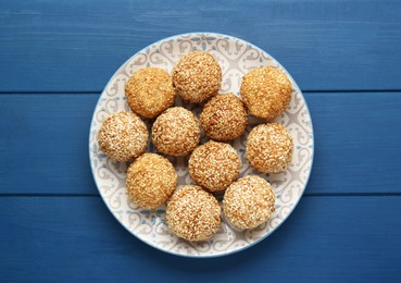 Photo of Delicious sesame balls on blue wooden table, top view