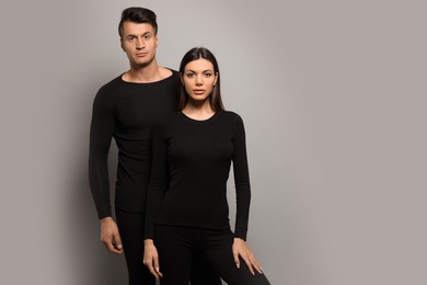 Couple wearing thermal underwear on grey background. Space for text