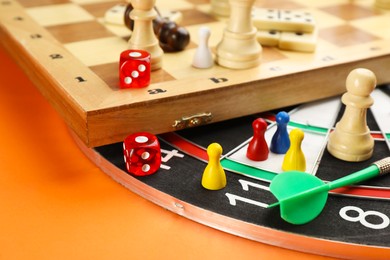 Different types of board games and its' components on orange background, closeup