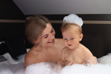 Mother with her child taking bubble bath together indoors