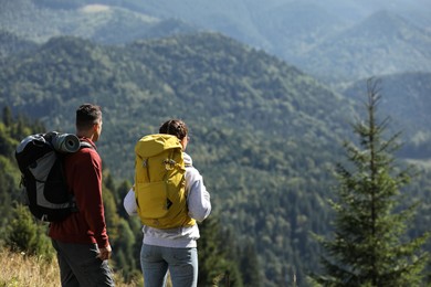 Couple with backpacks enjoying mountain landscape on sunny day