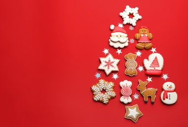 Delicious gingerbread cookies arranged in shape of Christmas tree on red background, flat lay. Space for text