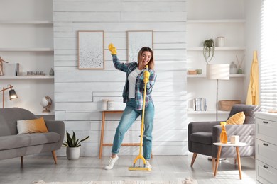 Woman with mop singing while cleaning at home