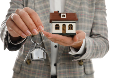 Real estate agent holding house model and key on white background, closeup