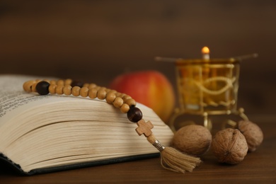 Bible, rosary beads, walnuts and apple on wooden table, closeup. Lent season