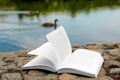 Photo of Open book on rocky shore near river