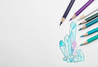 Drawing of crystals and colorful pencils on white background, top view