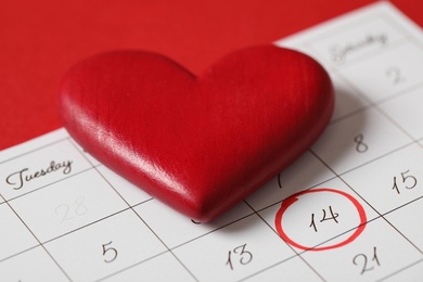 Calendar with marked Valentine's Day and heart on red background, closeup
