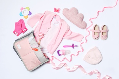 Composition with maternity bag and baby accessories on white background, top view
