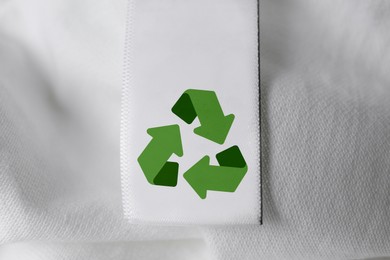 Clothing label with recycling symbol on white shirt, closeup view