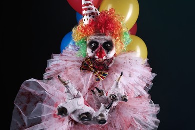 Terrifying clown with air balloons on black background. Halloween party costume