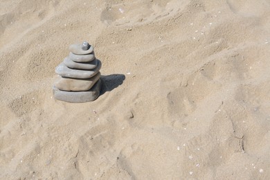 Stack of stones on beautiful sandy beach, space for text