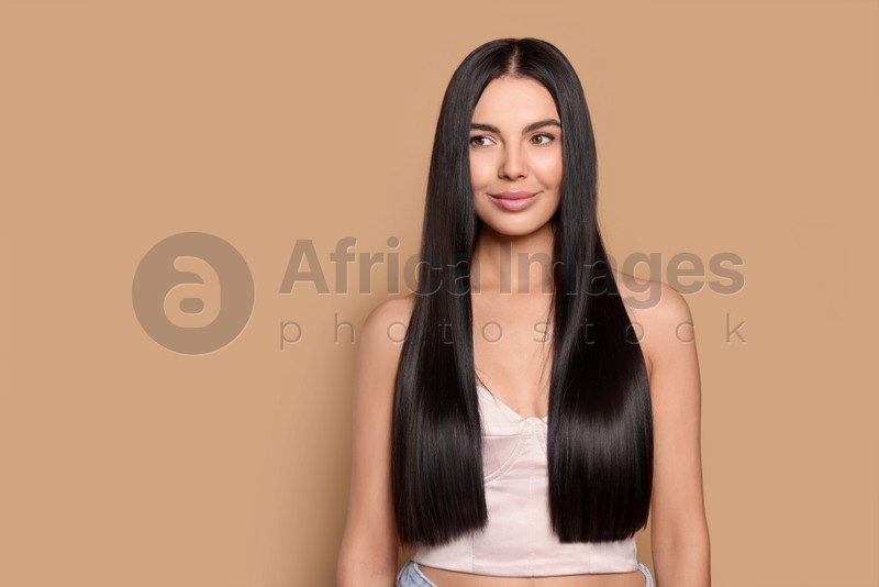 Portrait of beautiful young woman with healthy strong hair on beige background, space for text