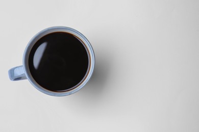 Mug of freshly brewed hot coffee on white background, top view. Space for text